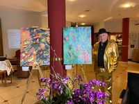 M. Wimmershoff im goldenen Anzug mit zwei Kunstwerken im Foyer des Victor's Residenz-Hotel Saarbrücken am Deutsch-Französischen Garten
